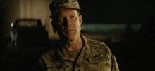 a man in a u.s. army uniform stands in a dark room