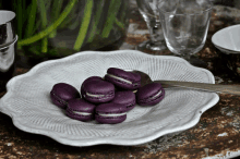 a white plate topped with purple macarons and a silver spoon