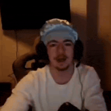 a man wearing headphones and a bandana on his head is sitting in front of a microphone .