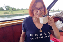 a woman wearing a shirt that says nasty woman drinking from a cup