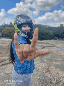 a woman wearing a helmet makes a peace sign with her hand