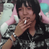 a woman is smoking a cigarette in front of a pink stuffed animal .