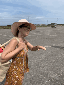 a woman wearing a hat and glasses is standing in an empty parking lot