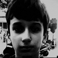 a black and white photo of a boy 's face with a motorcycle in the background .