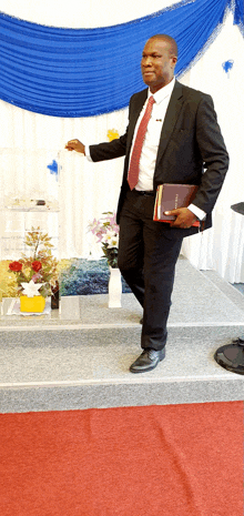 a man in a suit and tie holds a bible in his hand