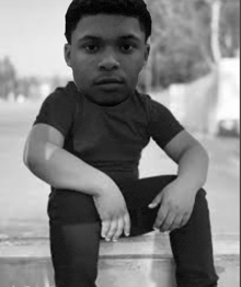 a black and white photo of a boy sitting on a bench with his head on his lap .