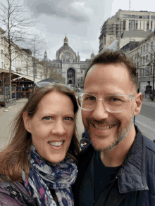 a man and a woman are posing for a picture with a building in the background