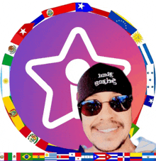 a man wearing sunglasses and a beanie that says jump engine is smiling in front of a circle of flags