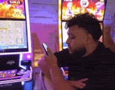 a man looking at his phone in front of a machine that says $ 190.23 on it