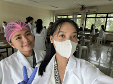 a woman wearing a lanyard that says biology stands next to another woman wearing a mask