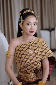 a woman wearing a gold and red dress with a necklace and earrings