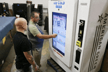 two men are looking at an ice cold beer machine