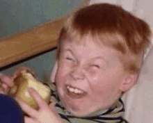 a young boy is making a funny face while holding a piece of banana .