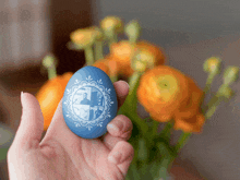 a person is holding a blue egg with a picture of a man and a woman on it