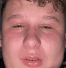 a close up of a young man 's face with tears running down his face .