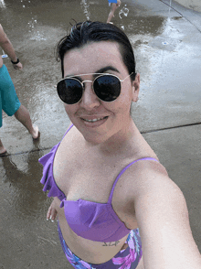 a woman wearing sunglasses and a purple bikini smiles for the camera