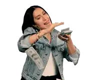 a woman in a denim jacket is holding a bunch of money in her hand