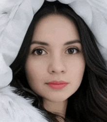 a close up of a woman 's face with a white fur coat covering her head .