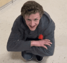 a young man is squatting on the floor with his arms crossed