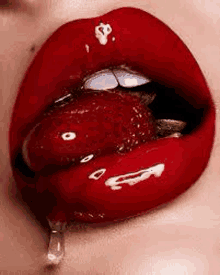 a close up of a woman 's lips with red lipstick and a strawberry sticking out of it .