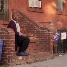 a man sits on a set of brick steps next to a sign that says ' i voted ' on it