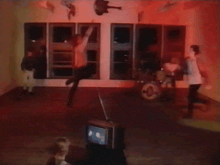 a blurry photo of people dancing in a room with a tv in the foreground