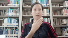 a woman stands in front of a bookshelf with a sign that says ' i love you ' on it