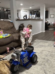 two little girls playing in a living room with a pantry sign on the wall behind them