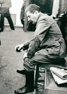 a man is sitting on a stool in a room .