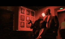 a man in a suit stands in front of a wall of pictures