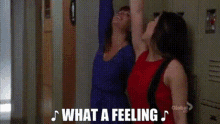 two women are standing next to each other with their arms in the air and the words `` what a feeling '' .