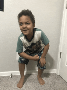 a young boy squatting down with his fist in the air wearing a shirt that says ' avengers ' on it