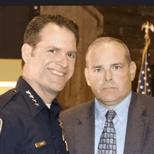 a police officer and a man in a suit pose for a picture