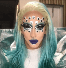 a drag queen with a wig and makeup has a lot of googly eyes on her face