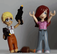 a boy holding a gun next to a girl with her arms up