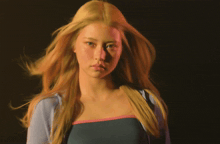 a woman with long blonde hair wearing a blue shirt