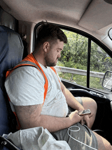 a man is sitting in a car looking at his cell phone