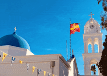 a clock tower with a blue dome and a red and yellow flag flying in front of it