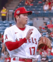 a baseball player wearing a red hat and a white jersey with the number 17 on it is standing in a stadium .