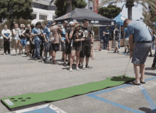 a group of people are playing a game of golf in a parking lot in front of a tent that says brewed