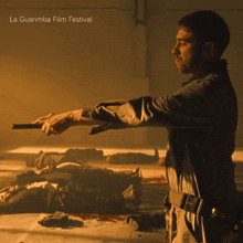 a man holding a gun in a dark room with la guarimba film festival written on the top