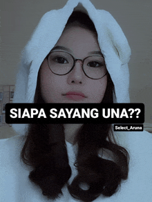 a woman wearing glasses and a white hoodie with the words siapa sayang una on the bottom