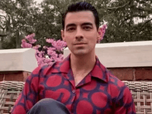 a man in a red and purple shirt is sitting on a wicker chair .