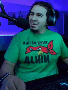 a man wearing headphones and a green t-shirt that says " a m'i em t2jat "