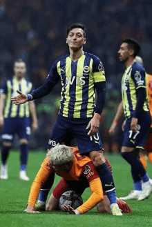 a soccer player is kneeling on top of another player during a soccer game .