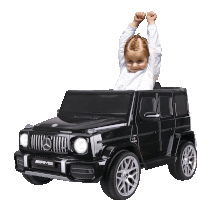 a little girl is sitting in a black mercedes amg car