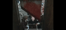 a man and a woman are standing in an elevator with blood coming out of the door .