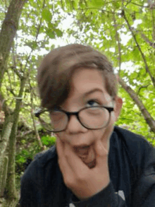 a young boy wearing glasses and a black shirt is making a funny face .