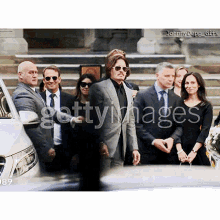 a man in a suit and sunglasses is standing in front of a group of people with the word getty images on the bottom right