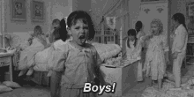 a black and white photo of a little girl standing in front of a group of children in a bedroom .